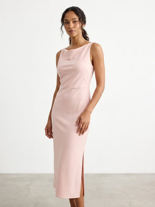 Model wearing a light pink sleeveless dress sitting indoors