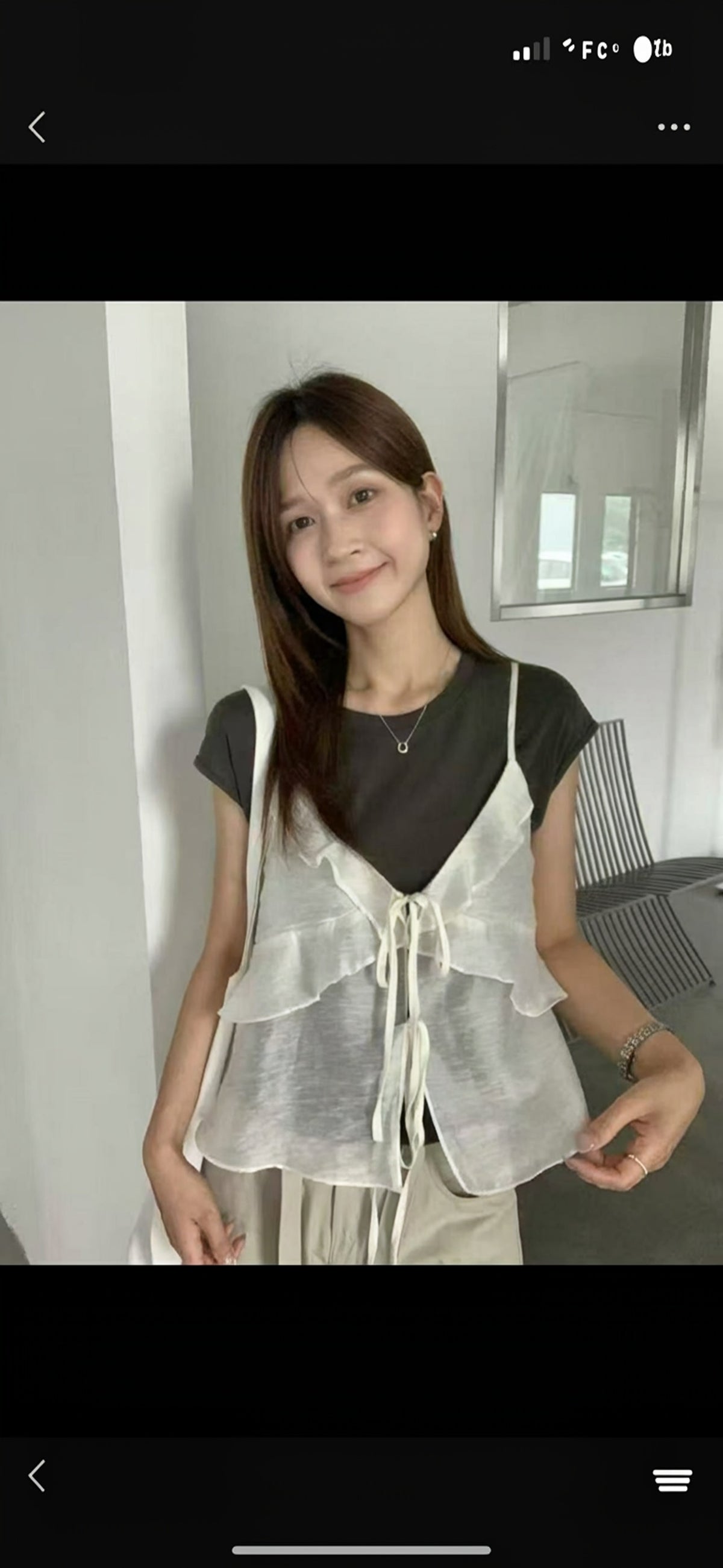 Model wearing a white ruffled tie-front sheer camisole over a t-shirt