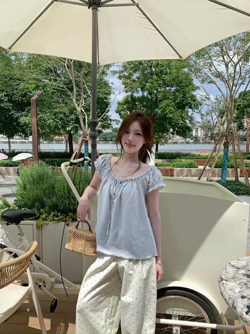 Woman standing outdoors wearing a light blue gathered tie-front short sleeve top