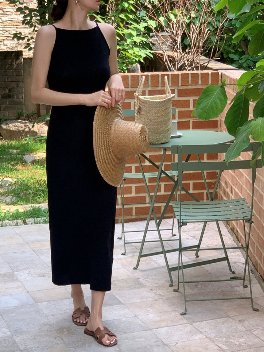 Woman modeling a black sleeveless midi dress with a straw hat