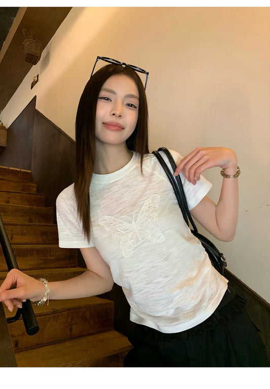 Model wearing white butterfly embroidered t-shirt on stairs