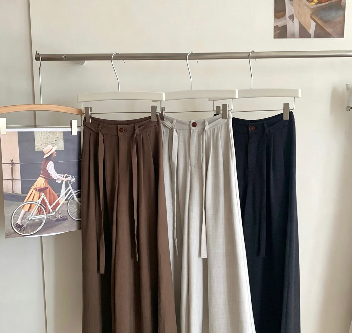 Draped wide-leg pants hanging on a rack showing front pleats
