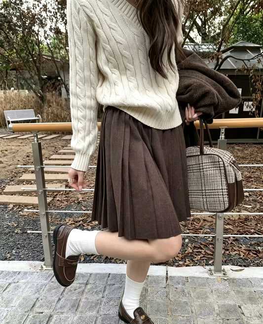 Model in dark brown knit pleated skirt and white cable knit sweater