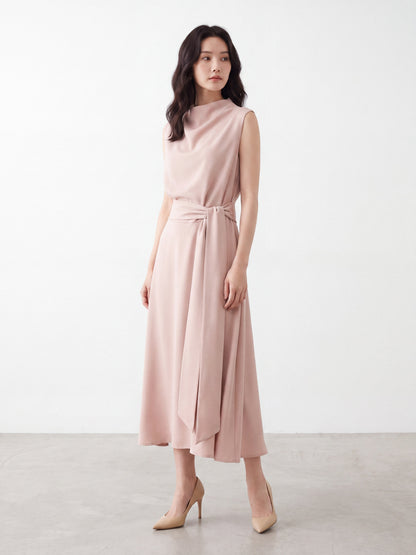 Model wearing apricot pink draped neck sleeveless dress with tie waist