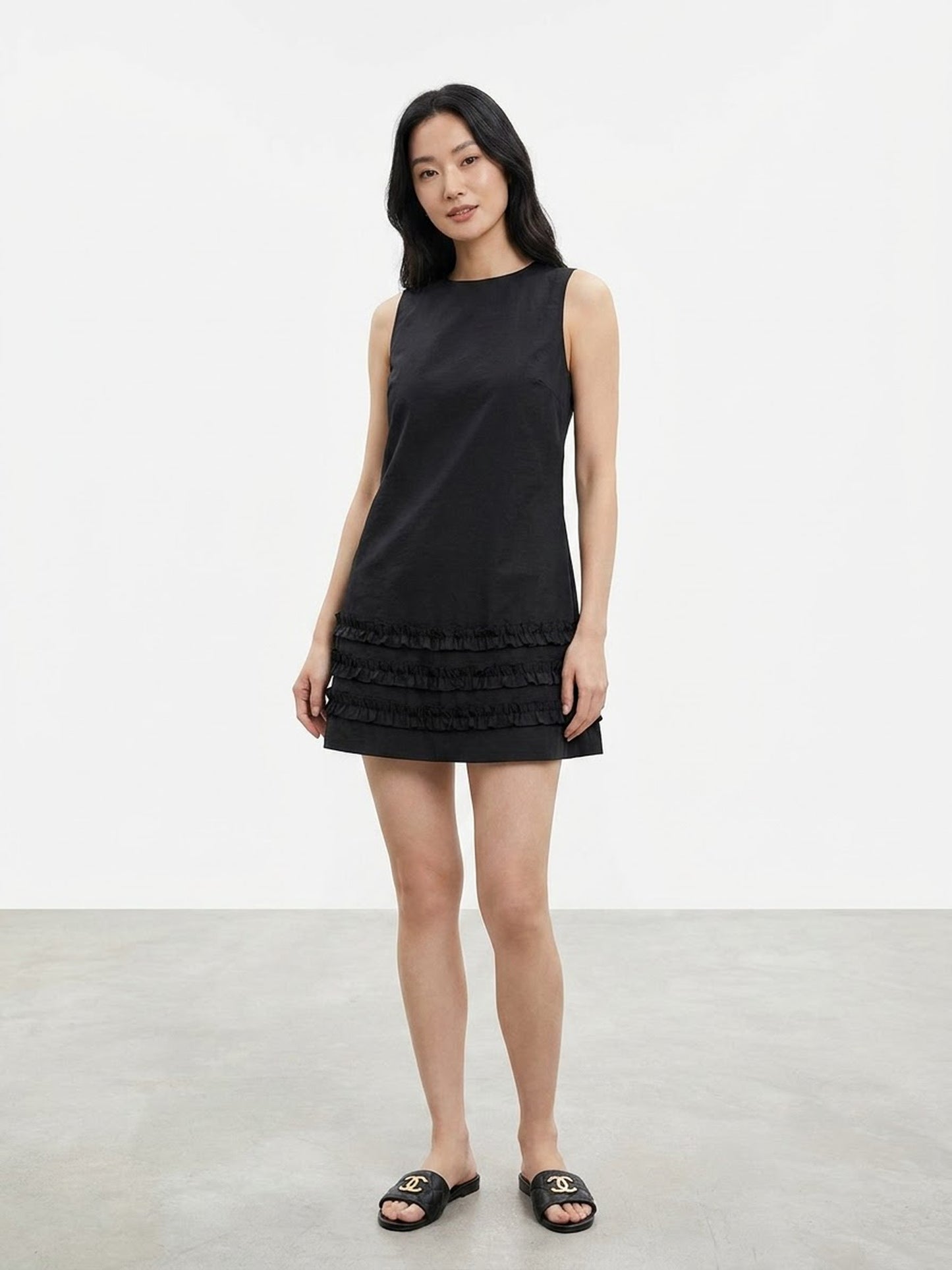 Model wearing black sleeveless ruffle hem mini dress