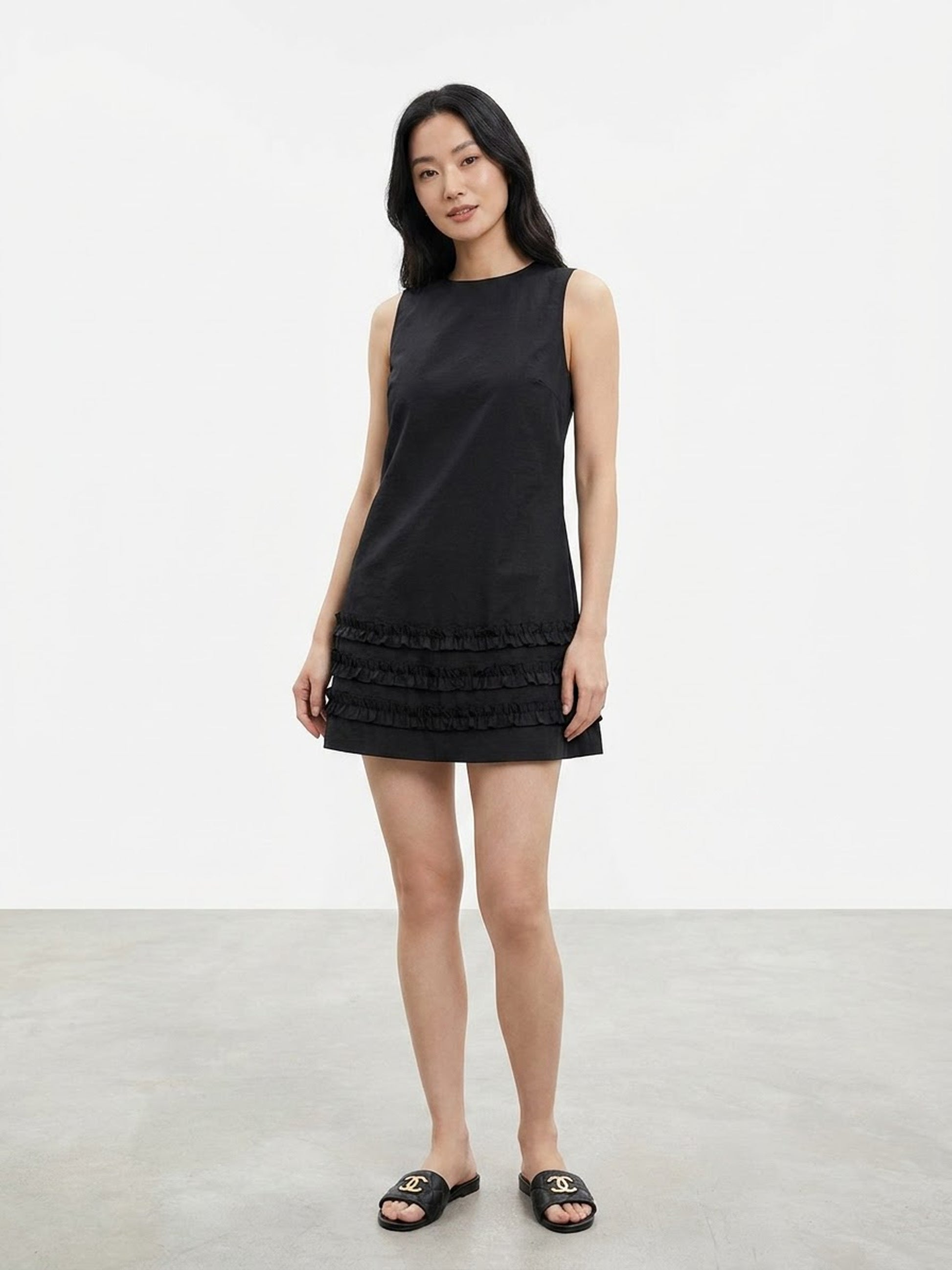 Model wearing black sleeveless ruffle hem mini dress