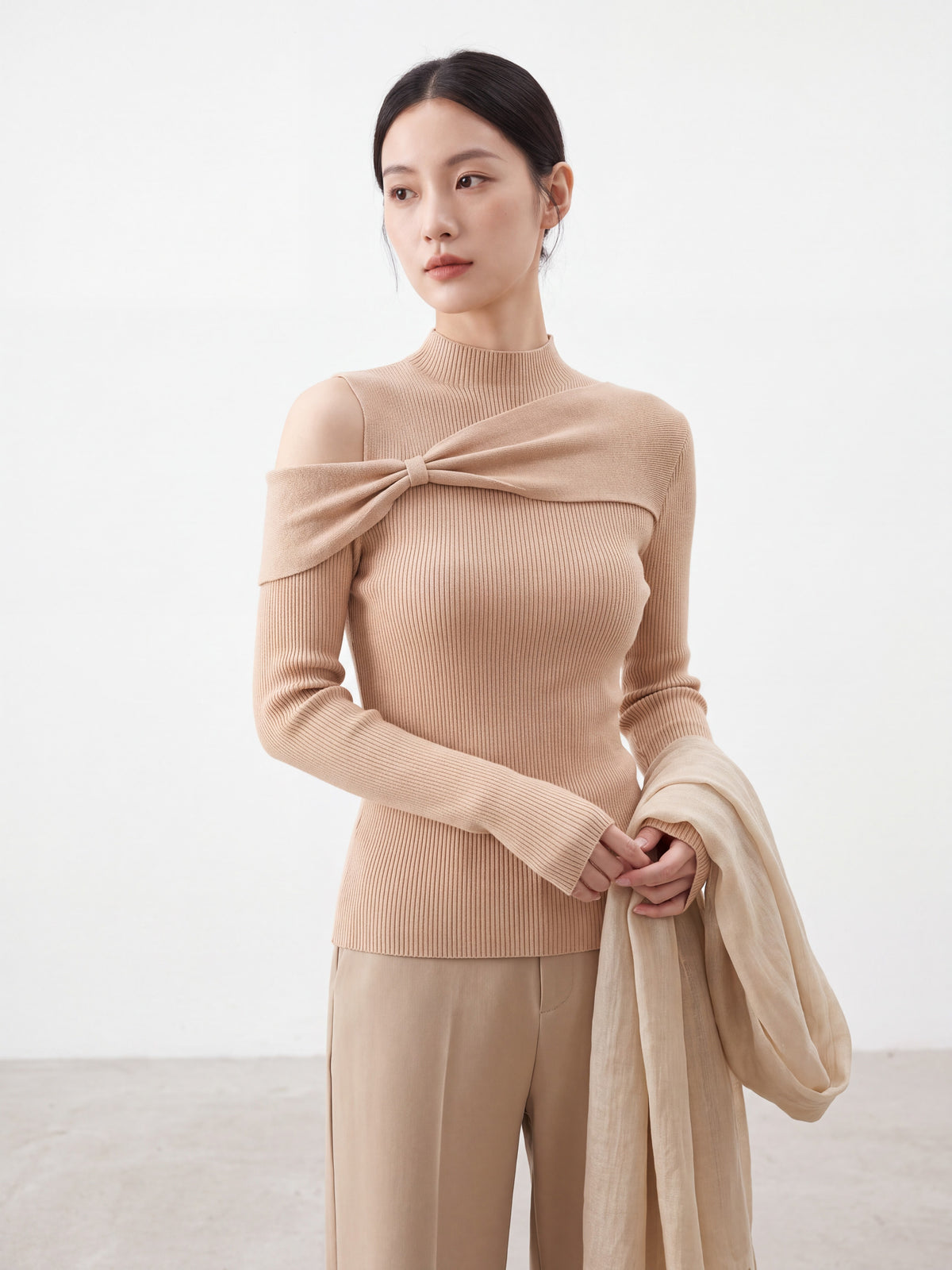 Model wearing orange-pink bow twist cold shoulder knit top, smiling