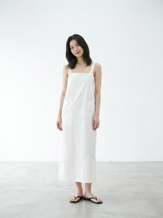 Woman taking a mirror selfie wearing a white overall dress