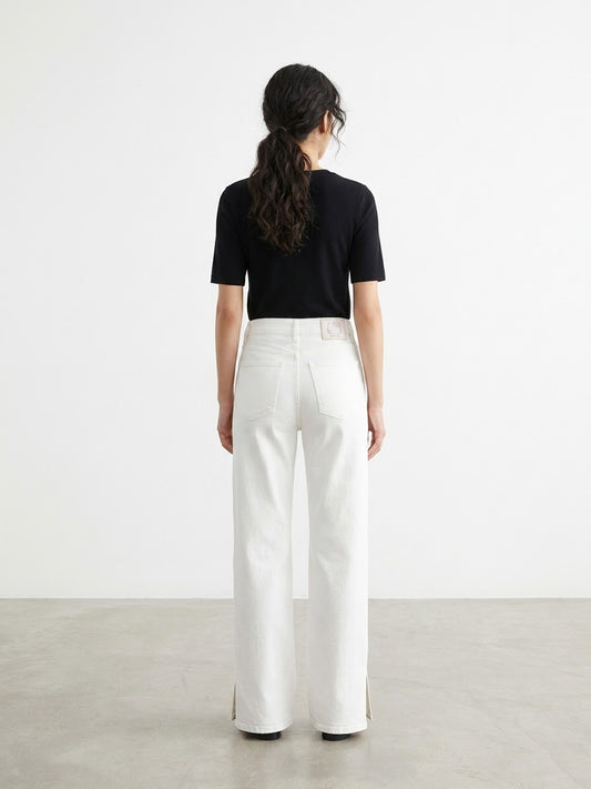 Back view of model wearing white cropped jeans with Hello Kitty leather patch