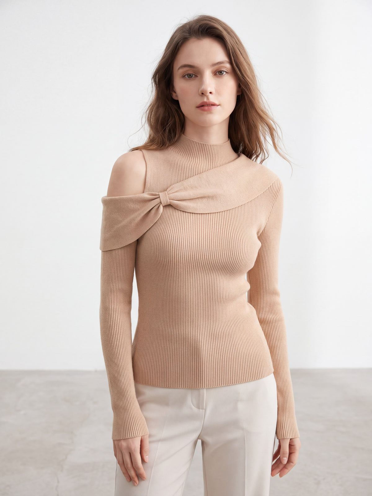 Model wearing orange-pink bow twist cold shoulder knit top