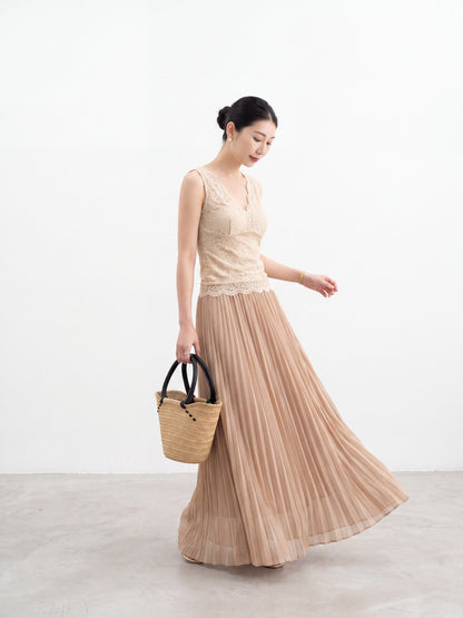 Model wearing an apricot pleated maxi skirt walking in a hallway