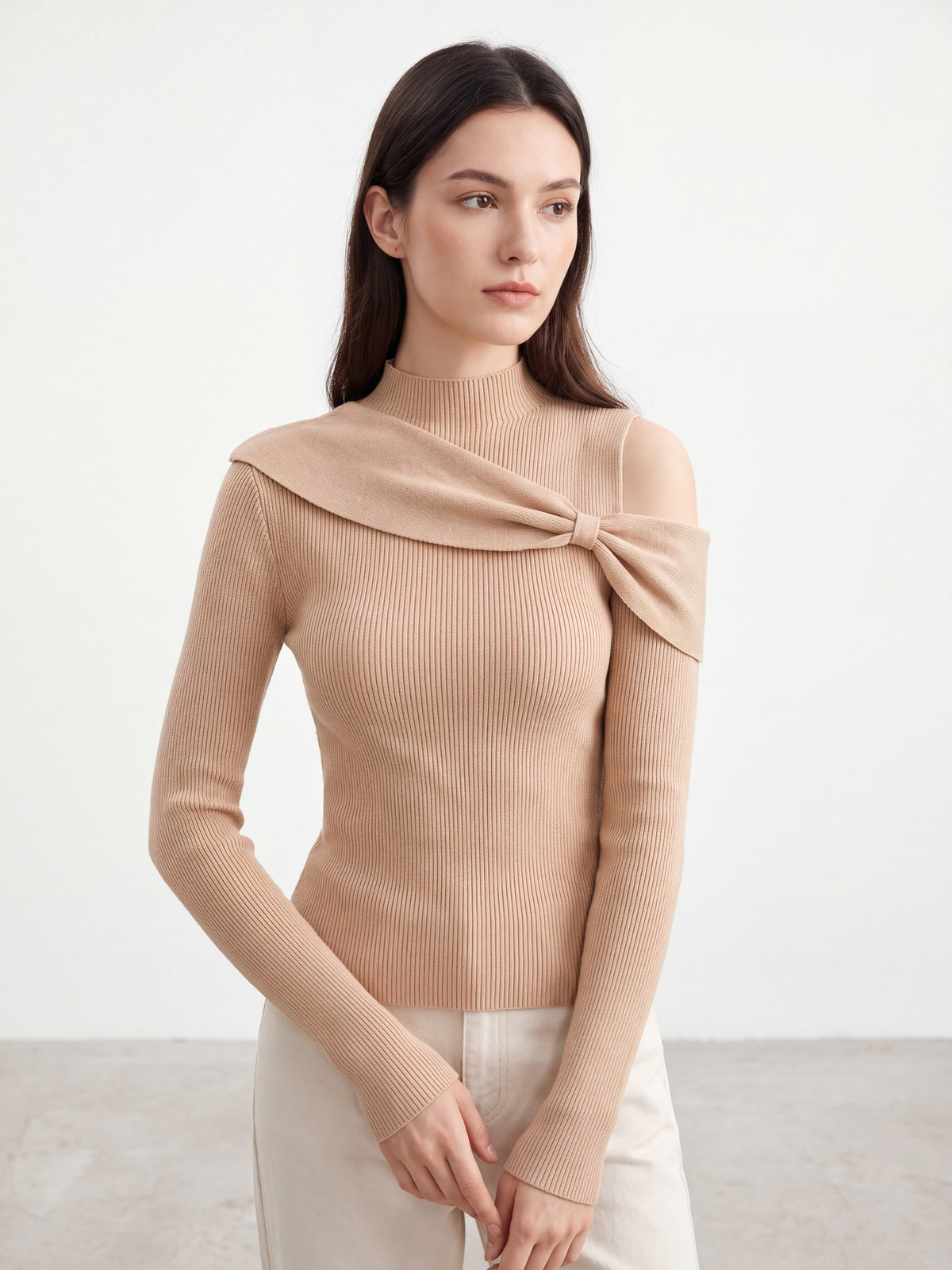 Model wearing orange-pink bow twist cold shoulder knit top, posing