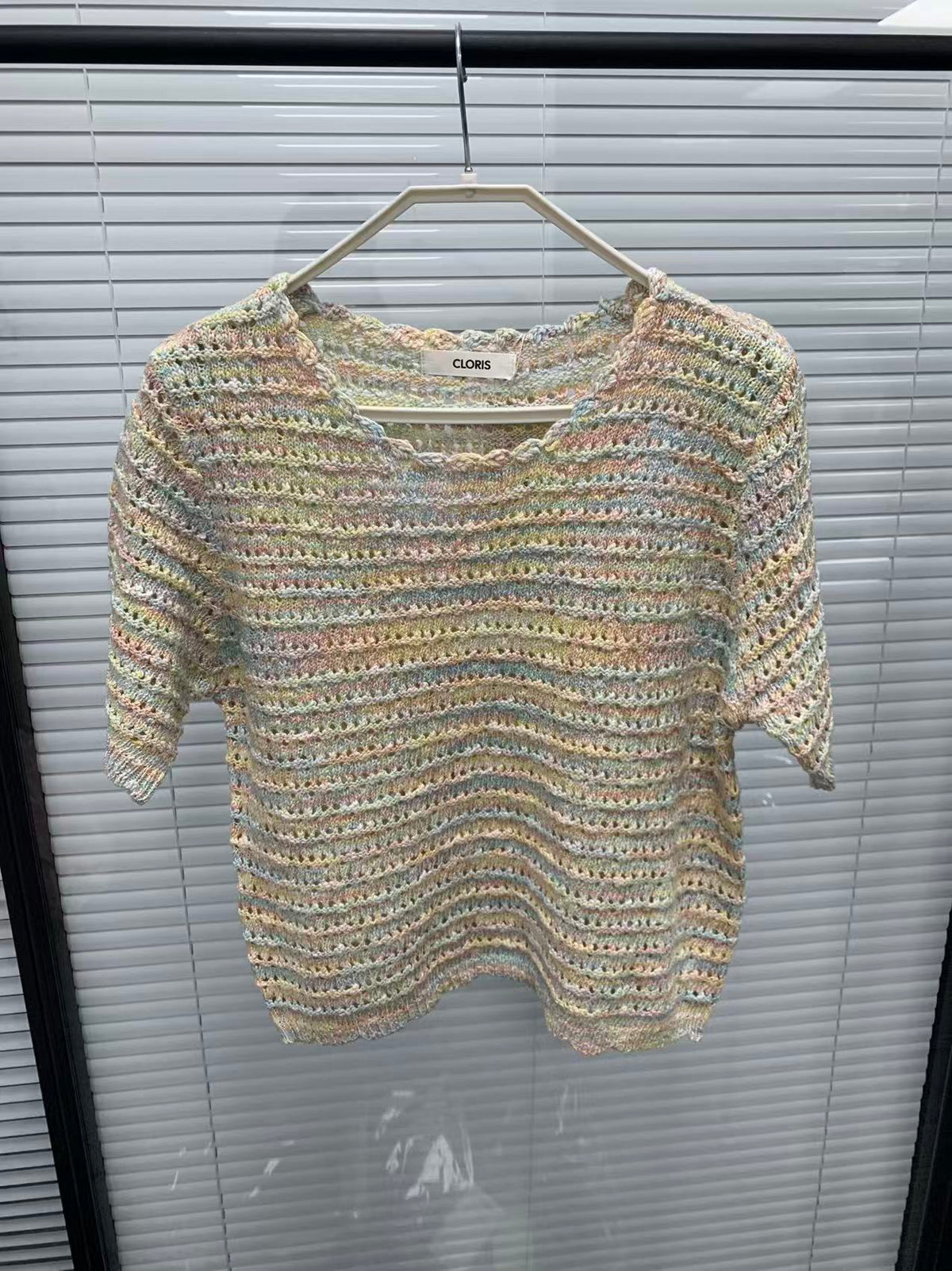 Pastel rainbow open-knit short-sleeve top on a hanger