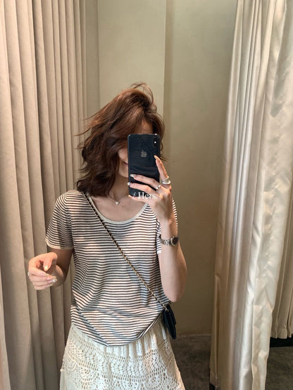 Woman wearing an oatmeal striped round neck short sleeve linen knit shirt taking a mirror selfie