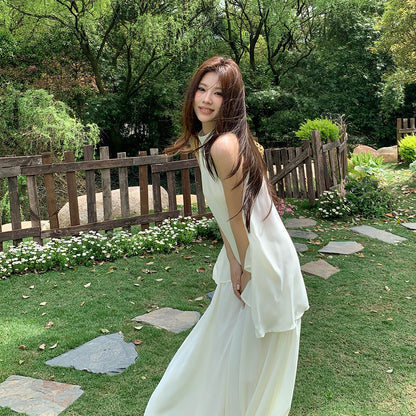 Woman in a white halter neck top and long skirt standing outdoors