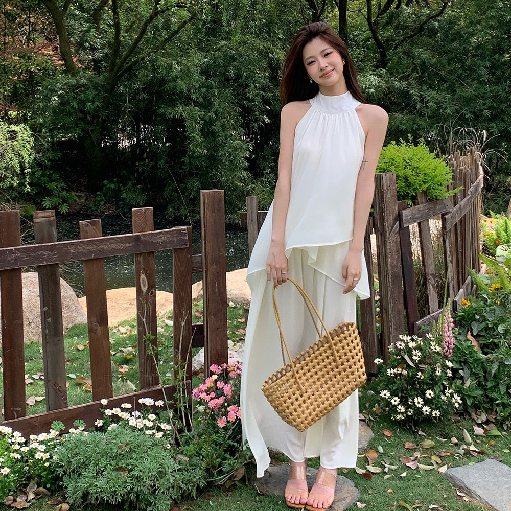 Woman wearing a white flowy summer set holding a woven bag
