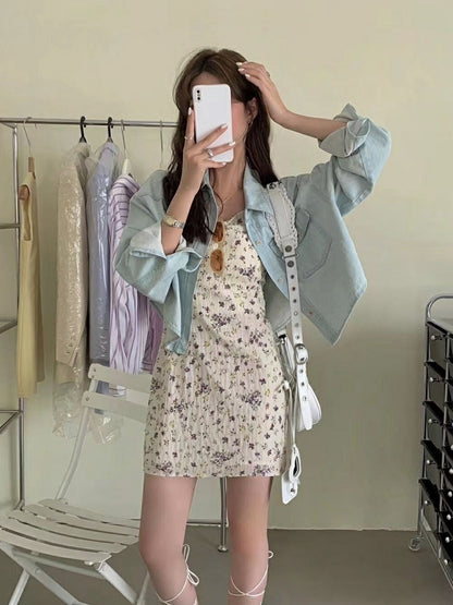 Close-up of a woman taking a mirror selfie wearing a light blue denim jacket over a floral mini dress