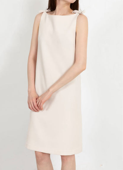 Model showcasing the front of the off-white sleeveless dress with shoulder bows.