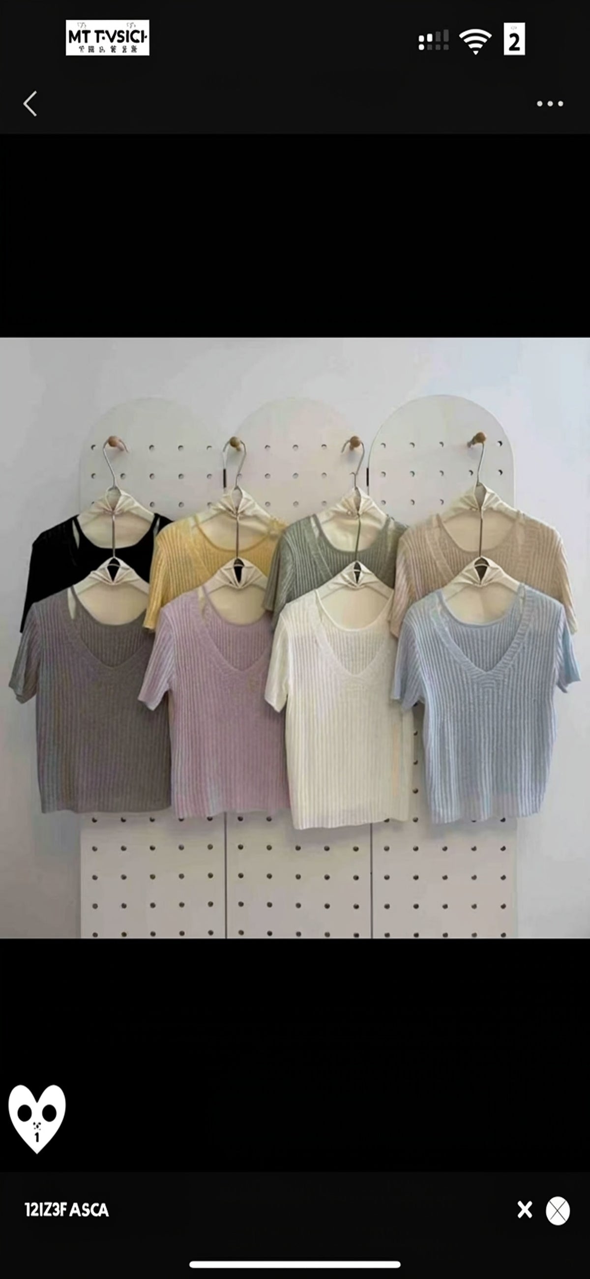 Multiple colors of faux two-piece V-neck ribbed knit short-sleeve tops hanging on a pegboard
