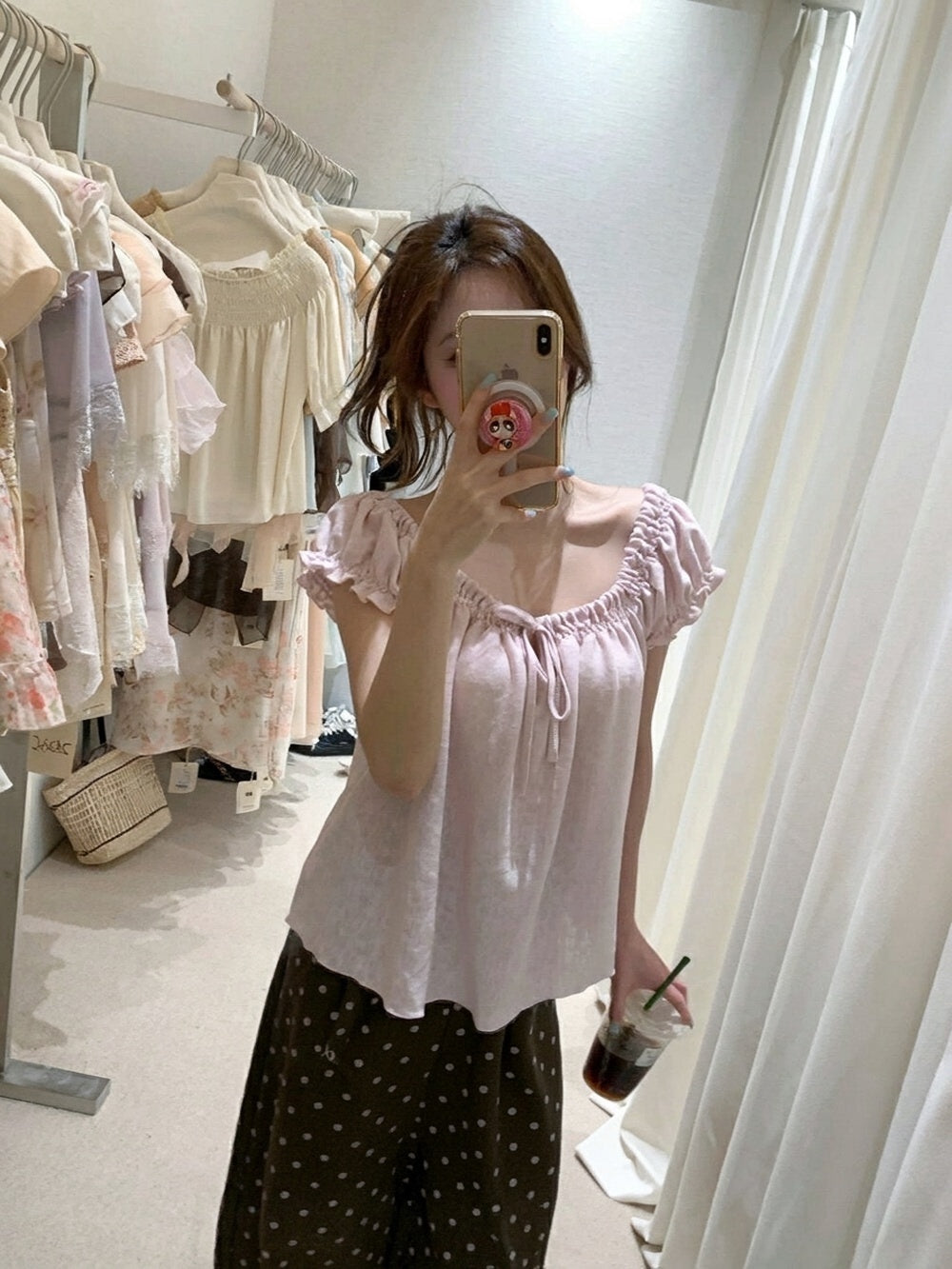 Woman taking a mirror selfie wearing a pink gathered tie-front short sleeve top