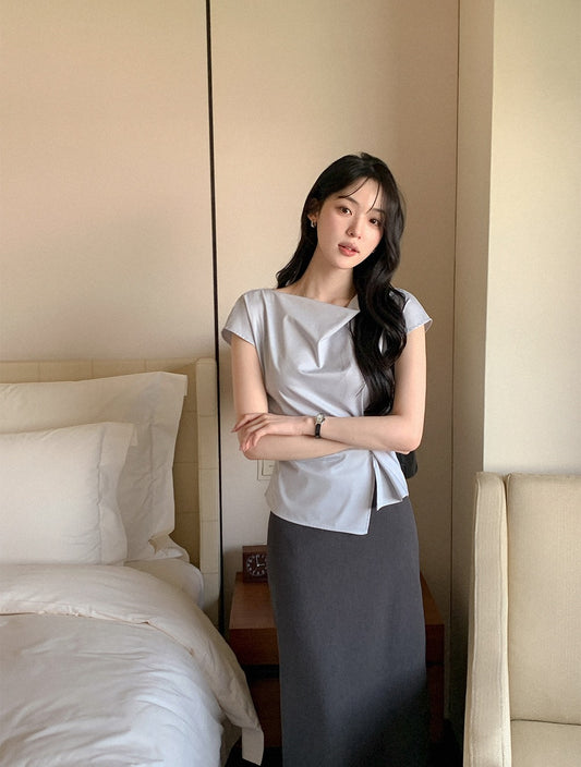 Woman modeling a light blue elegant draped neck top with side tie.