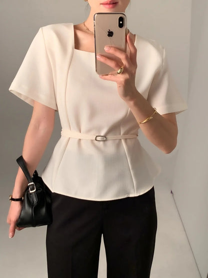 Woman wearing a white square neck short-sleeve peplum top with a thin belt