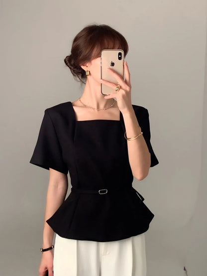 Woman wearing a black square neck short-sleeve peplum top with a thin belt