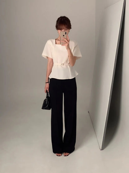 Woman wearing a white square neck short-sleeve peplum top with black wide-leg trousers