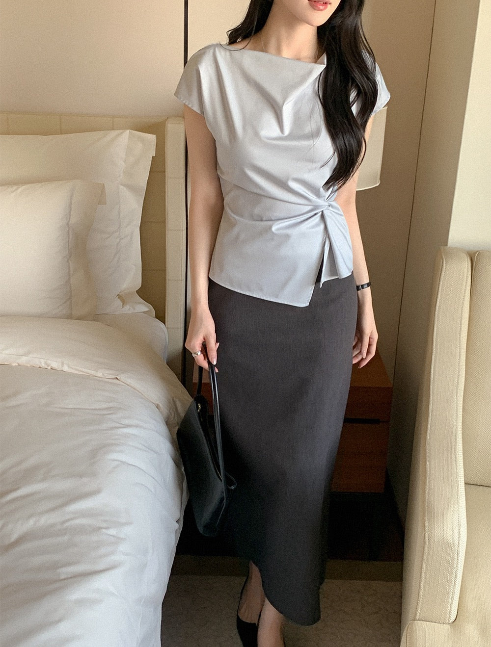 Close-up of a light blue asymmetrical short sleeve top with waist knot detail.
