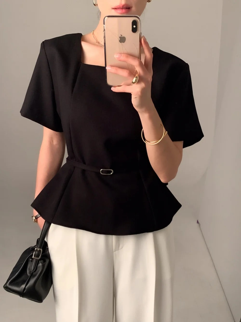 Woman wearing a black square neck short-sleeve peplum top with white trousers