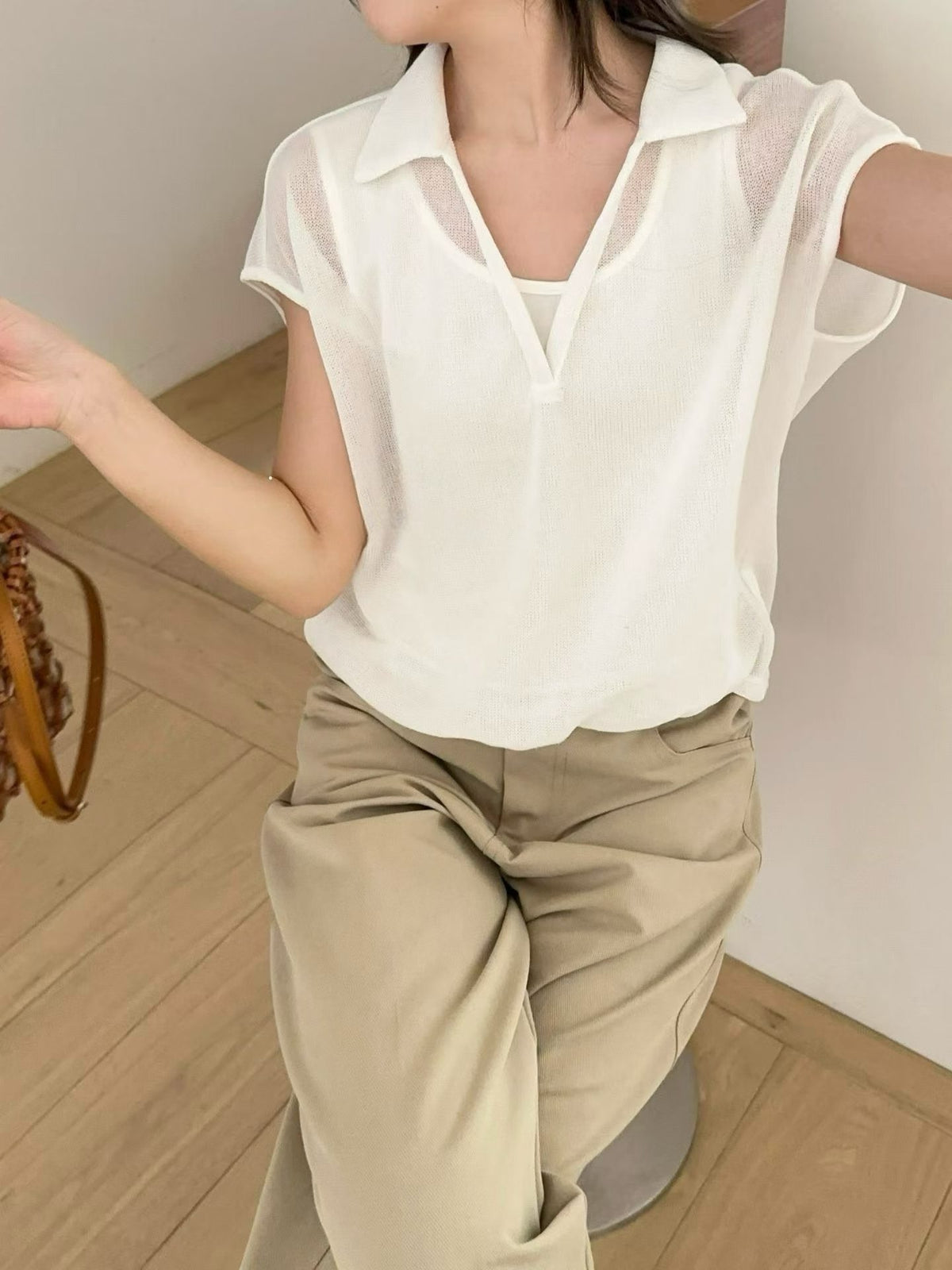 Model wearing a white sheer V-neck collared knit shirt with khaki pants.