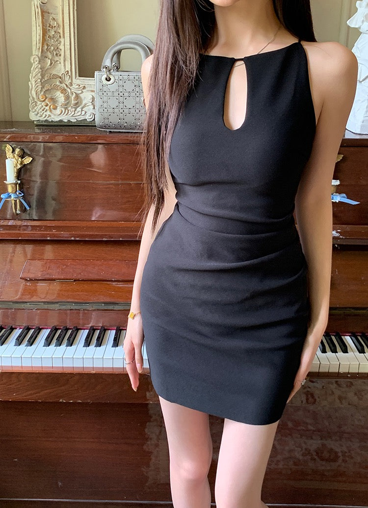 Model wearing a black keyhole sleeveless mini dress standing in front of a piano