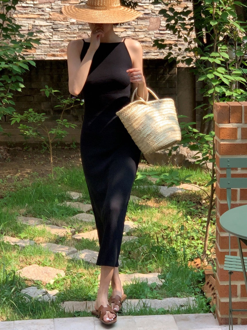 Woman in a black slip dress carrying a straw bag