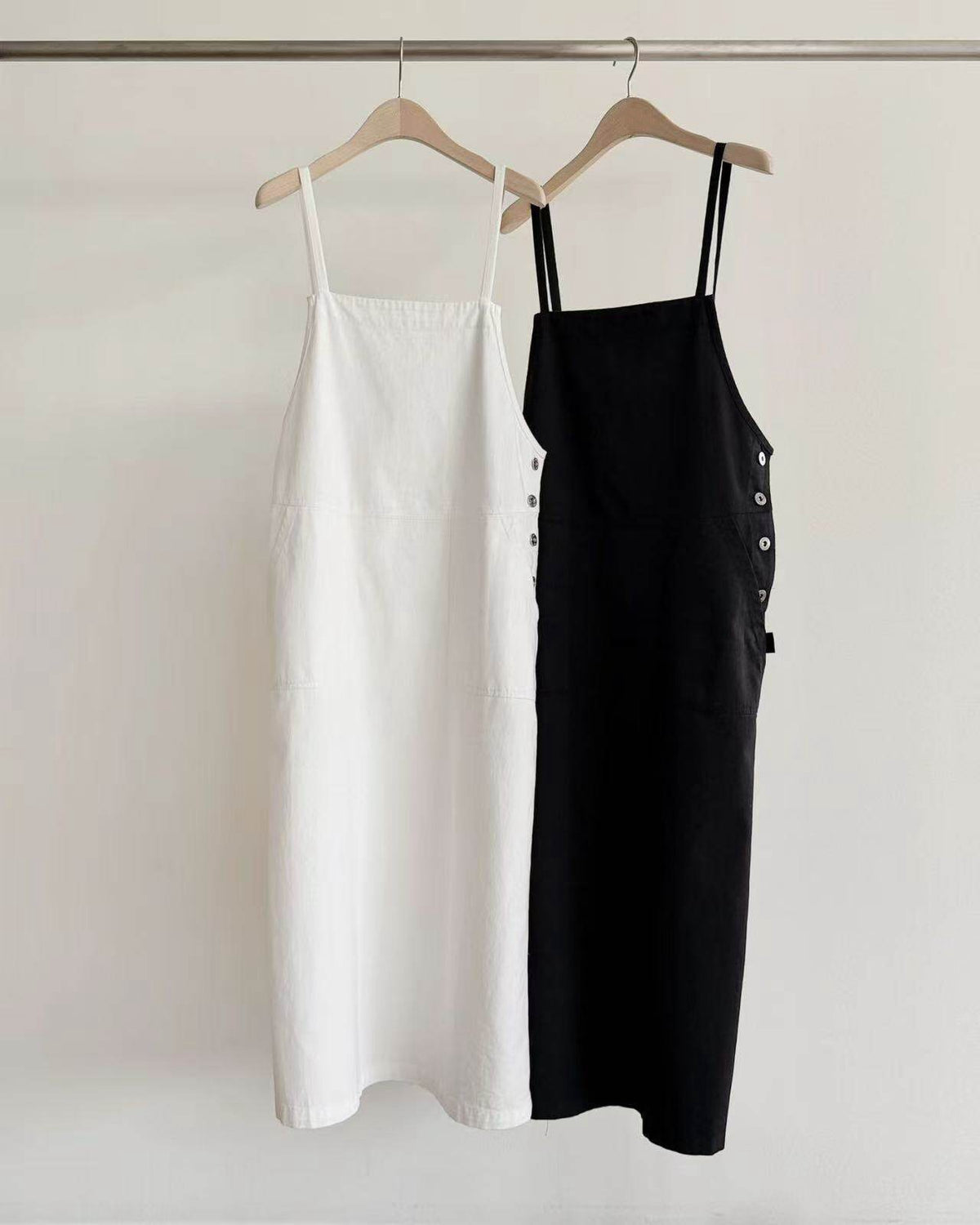 White and black overall dresses hanging on a clothing rack