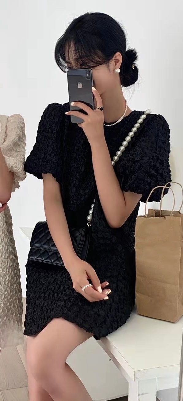 Mirror selfie of a woman in a black textured short-sleeved dress