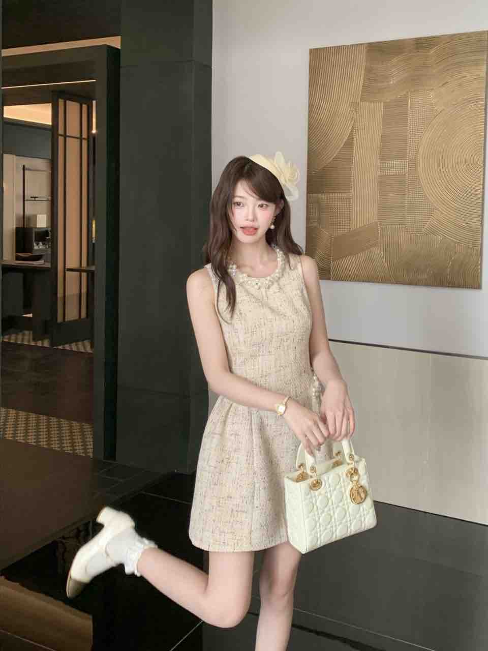 Model wearing an apricot tweed sleeveless dress with pearls