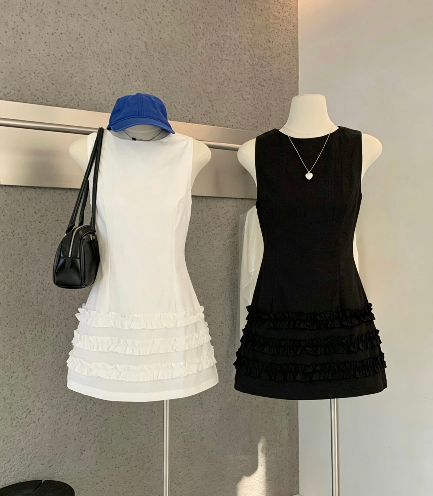 Mannequins displaying white and black sleeveless ruffle hem mini dresses