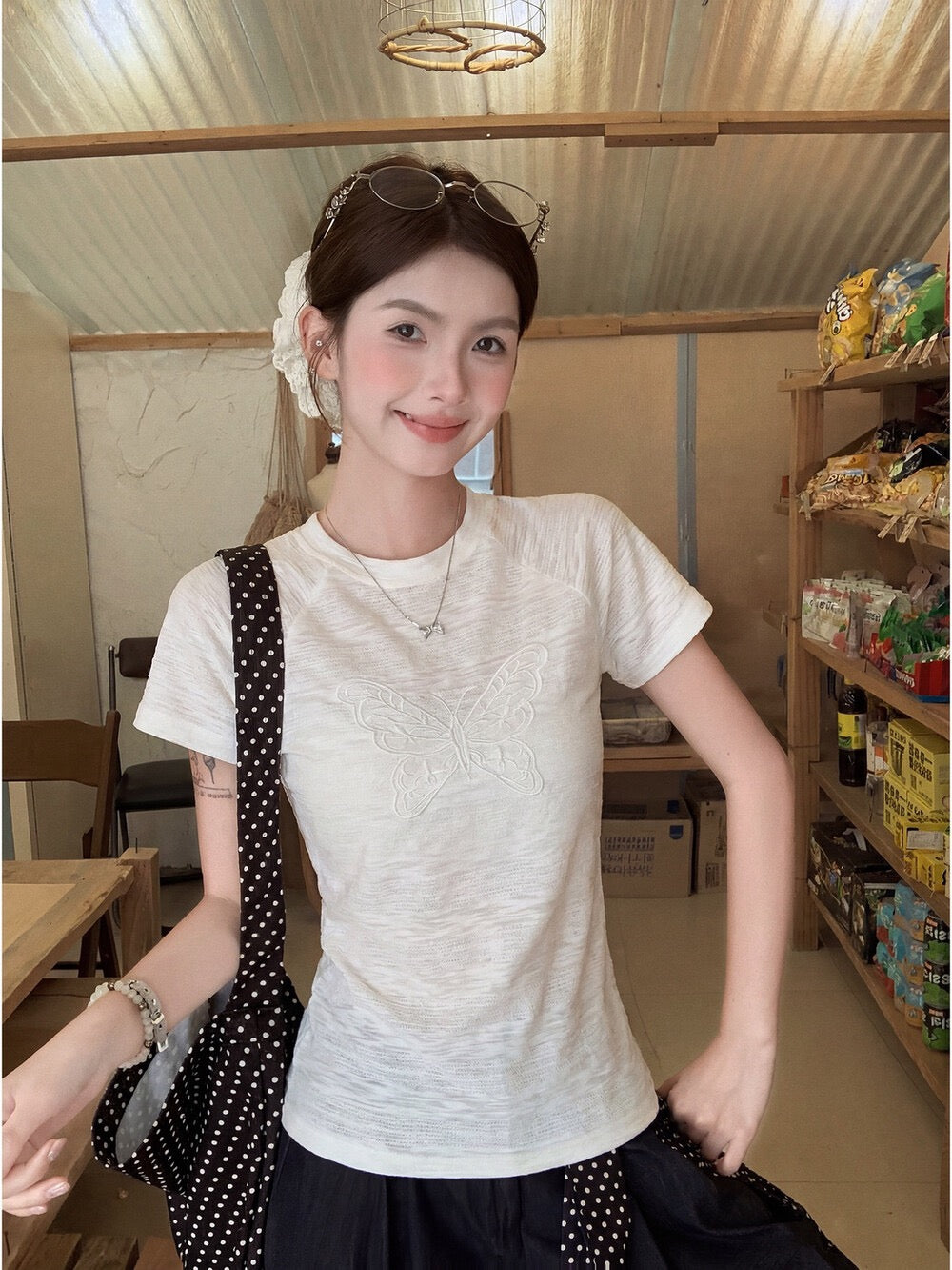 Model wearing white butterfly embroidered t-shirt smiling