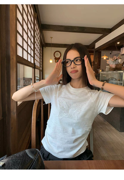 Model wearing white butterfly embroidered t-shirt adjusting glasses