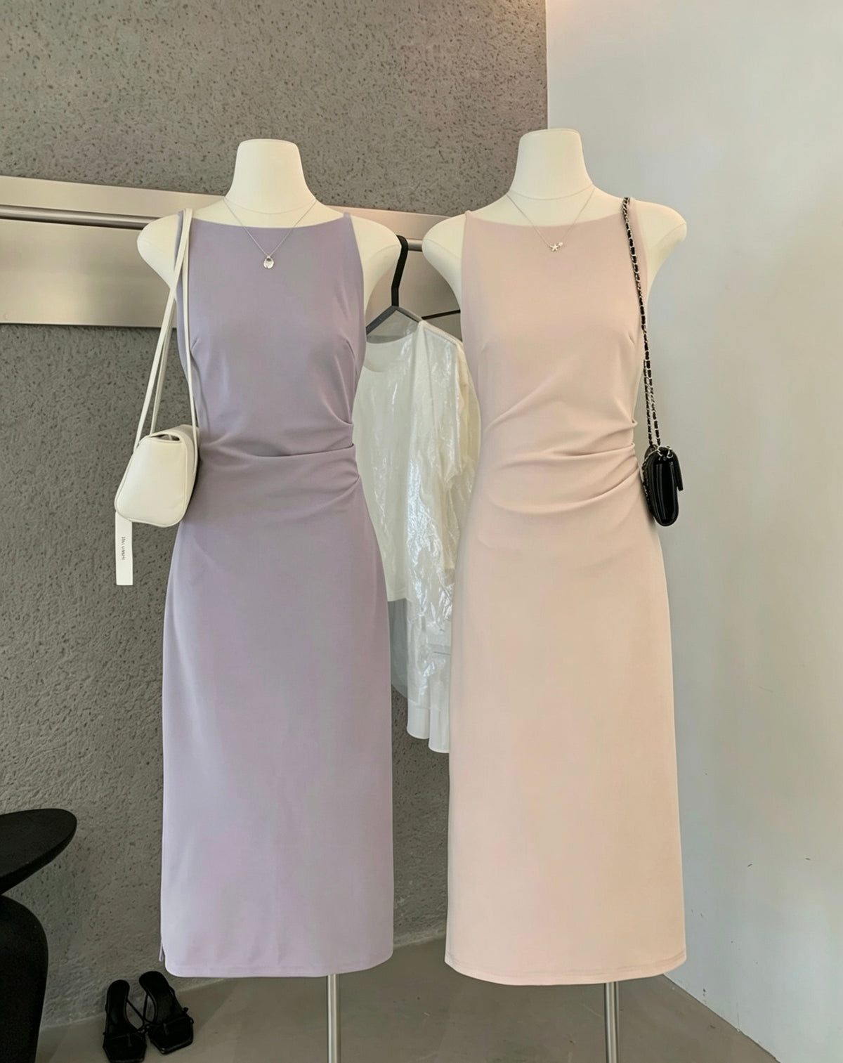 Two mannequins displaying sleeveless midi dresses in purple and pink