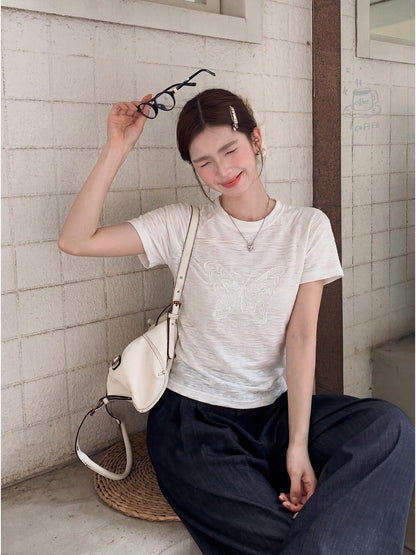 Model wearing white butterfly embroidered t-shirt holding glasses