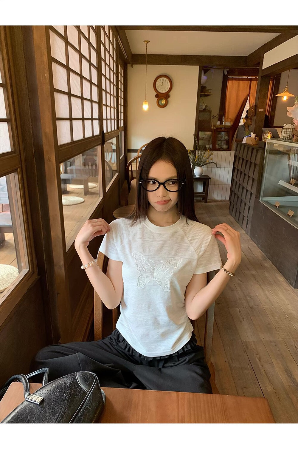Model wearing white butterfly embroidered t-shirt in cafe
