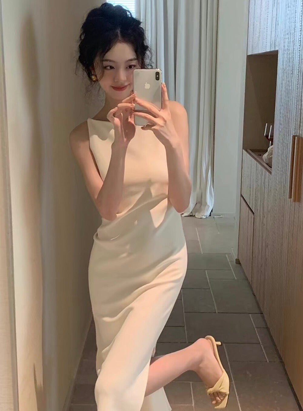 Woman taking a mirror selfie in a white sleeveless midi dress