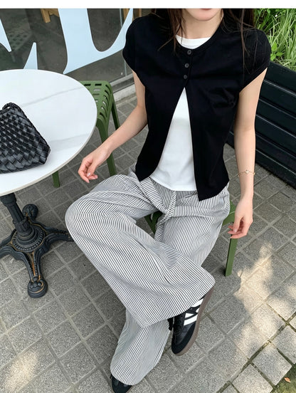 Model wearing a black faux two-piece short sleeve shirt sitting outdoors