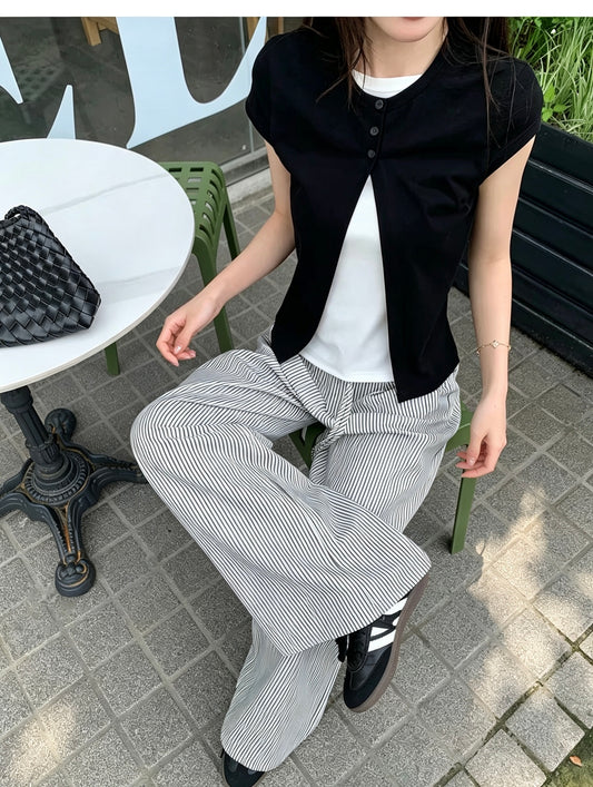 Model wearing a black faux two-piece short sleeve shirt sitting outdoors