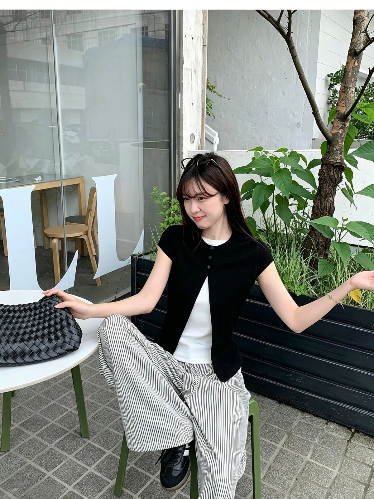 Model wearing a black faux two-piece short sleeve shirt sitting