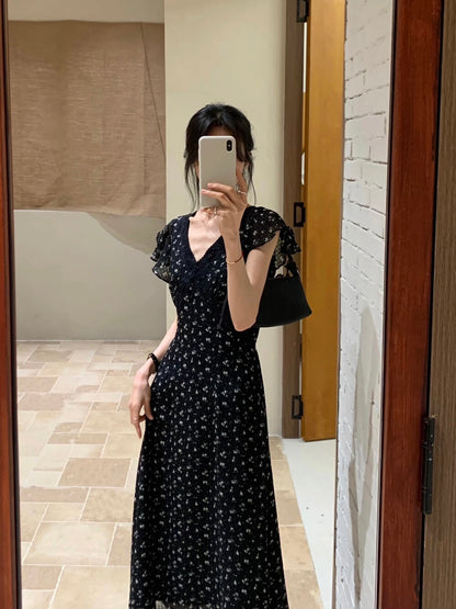 Mirror selfie of a woman wearing a black floral v-neck dress