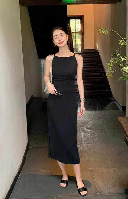 Model in a black sleeveless midi dress standing near a staircase