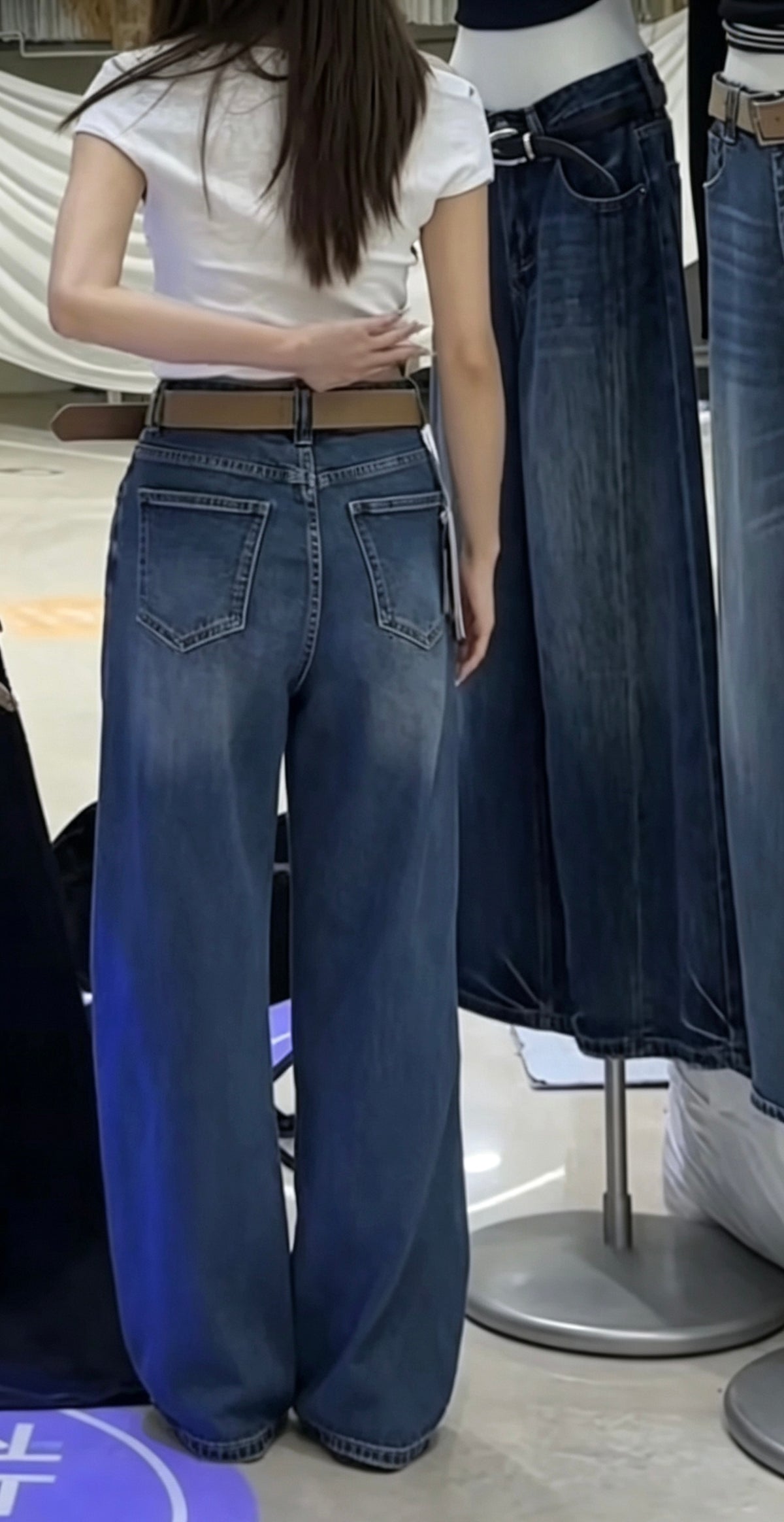 Model wearing dark blue straight jeans back view