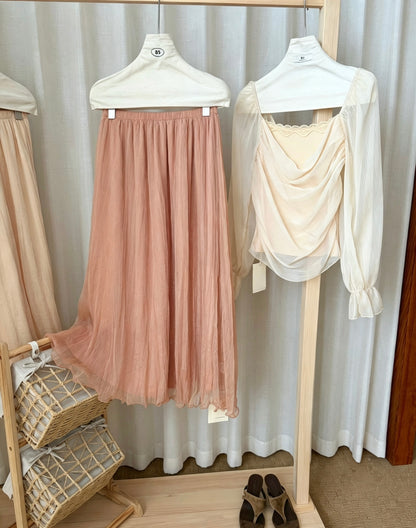Dark pink mesh skirt paired with a white long-sleeve top on a rack